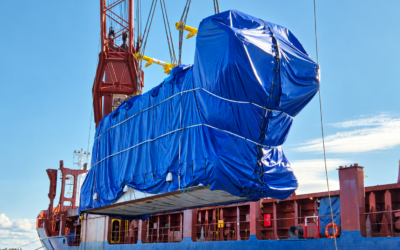 Oversized power plant cargo wrapped in blue tarpaulin during heavy-lift vessel loading, part of an international project cargo shipment.