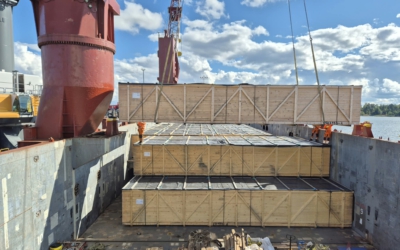 Wooden crates holding project cargo accessories, stacked in three tiers inside a vessel's hold and lifted into position by crane.